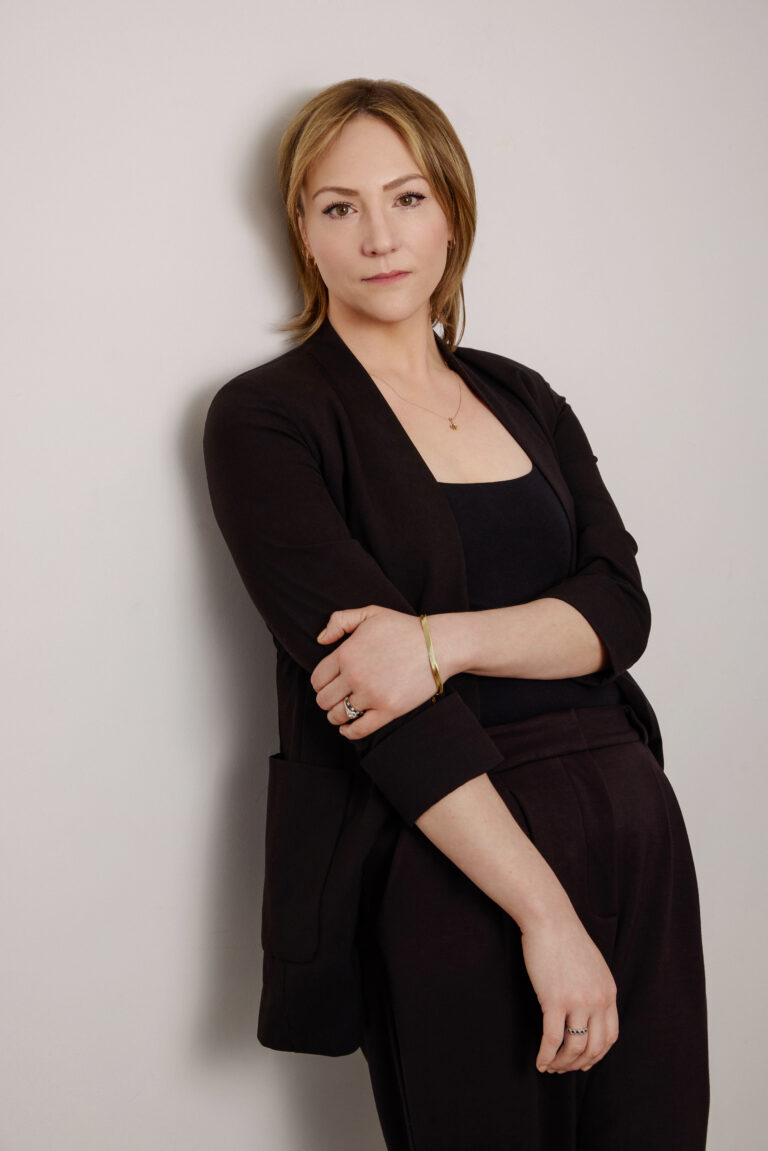 Professional woman in black outfit against white wall