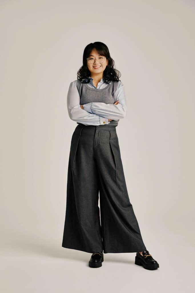 Smiling woman in glasses poses in gray business outfit